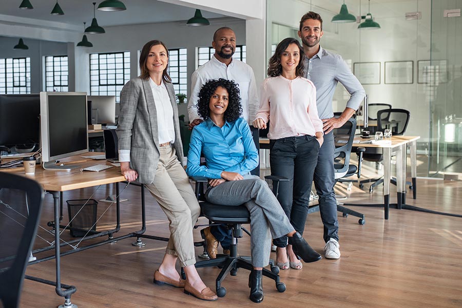 Employee Benefits - Coworkers Perch on a Work Table in a Large Modern Office